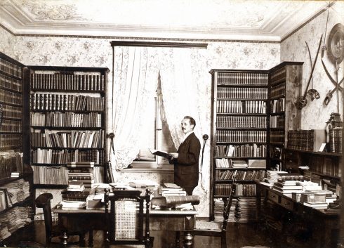 Karl May steht lesend in seiner Bibliothek, 1896